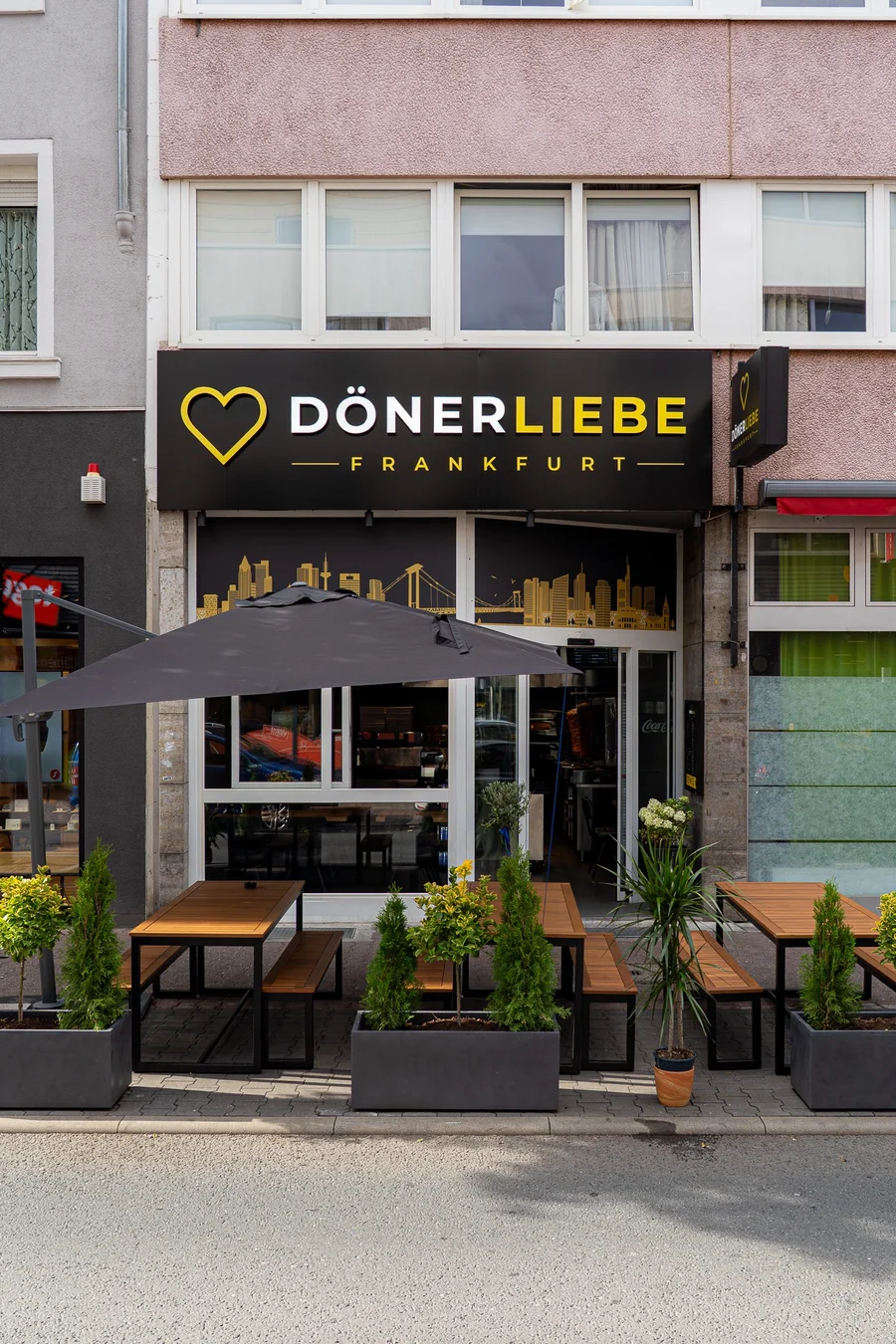 Der Eingang von DönerLiebe in der Radilostraße 16, mit gold-weißem Schriftzug und Sitzplätzen vor dem Laden.